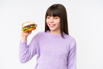 Little caucasian girl holding a burger over isolated background with happy expression