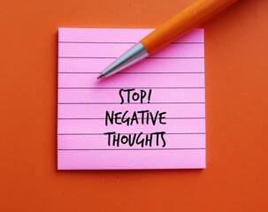 Pink note on orange background with pen written STOP NEGATIVE THOUGHTS, means stop attracting...