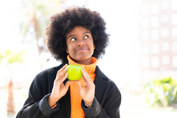 African American girl at outdoors holding an apple