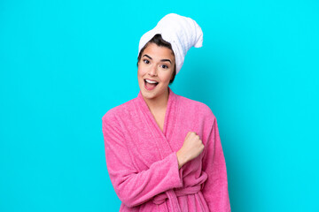 Young Brazilian woman with a bathrobe isolated on blue background celebrating a victory