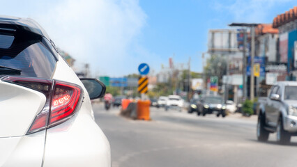 Obraz premium Rear side of white car driving or stop beside on the asphalt road. wtih other cars to beside in day time. blurred of buildings in the city of Thailand. 