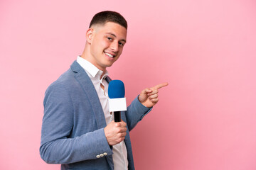 Young brazilian presenter man isolated on pink background pointing finger to the side