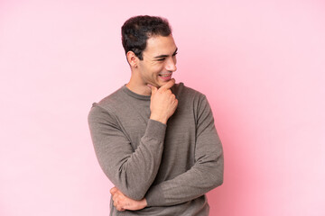 Young caucasian man isolated on pink background looking to the side and smiling