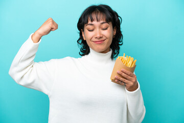 Young Argentinian woman holding fried chips isolated on blue background doing strong gesture