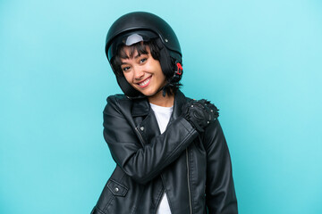 Young Argentinian woman with a motorcycle helmet isolated on blue background laughing