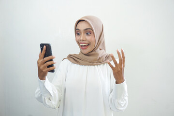 Excited beautiful Asian muslim woman showing mobile phone isolated over white background