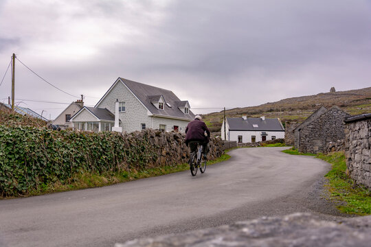 Cycling by old cottage in the village of Inishmore island