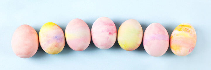 Painted Easter eggs in pink yellow and green on a blue background with a place for text. Happy Easter concept. Banner