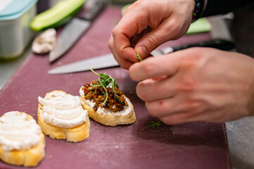man chef hand cooking tapas with tapenade and cream cheese on restaurant kitchen
