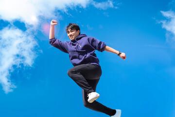 青空にジャンプする青年