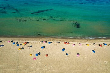 Aerial top view of colorful umbrellas on a beach against a blue sea on a sunny summer day