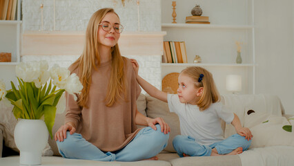 Mindful Caucasian mother calm woman meditating with closed eyes in lotus position doing yoga...