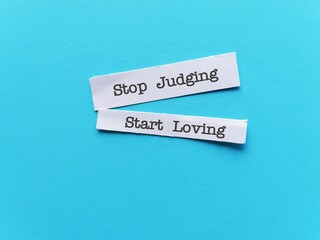 Pieces of paper on blue background with text STOP JUDGING START LOVING  - To remind to try judging...