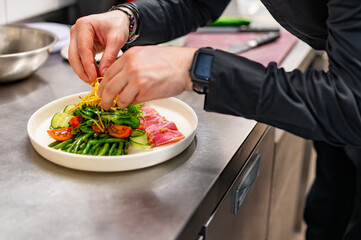 man chef hand cooking tuna slices with fresh vegetables and green beans salad on restaurant kitchen