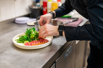 man chef hand cooking tuna slices with fresh vegetables and green beans salad on restaurant kitchen