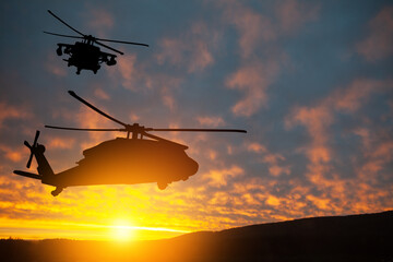 Naklejka na ściany i meble Silhouettes of helicopters on background of sunset.