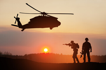 Naklejka na ściany i meble Silhouettes of helicopter and soldiers on background of sunset.