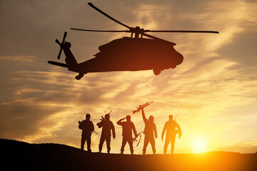 Naklejka na ściany i meble Silhouettes of helicopter and soldiers on background of sunset.