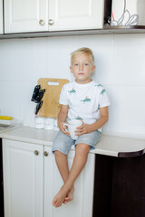 Happy relaxed young boy sitting in the kitchen, smiling, laughing, enjoying