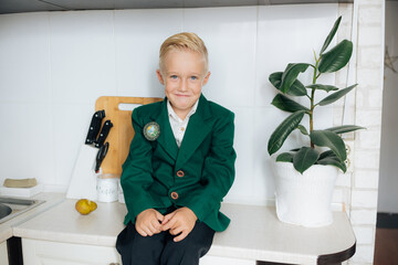 Happy relaxed young boy sitting in the kitchen, smiling, laughing, enjoying