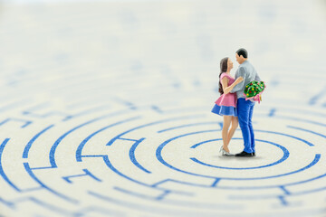 Overcoming obstacles together for married life, newly wed concept : Miniature couple embrace each other in a maze, depicts trouble or problems a new sweetheart will encounter bofore getting married.