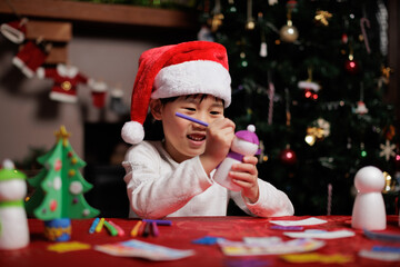 young girl wearing santa hat was making Christmas craft at home