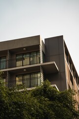 Low-angle of a modern residential apartment building and trees, with a bright sky in the background