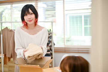 Beautiful Asian female fashion clothing seller packing a shipping product