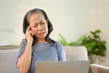 Unwell senior Asian woman suffering from her headache or migraine