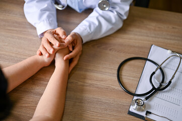 A doctor holding a patient's hands to comfort and reassure her during the meeting
