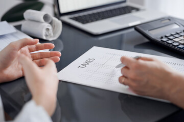 Woman accountant using a calculator and laptop computer while counting taxes for a client. Business...