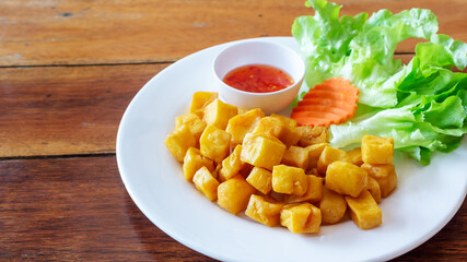 Fry tofu with spicy sauce and vegetables on a wooden table.