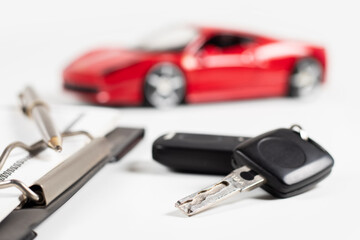 Car insurance form, pen and key on wooden table, and red car background