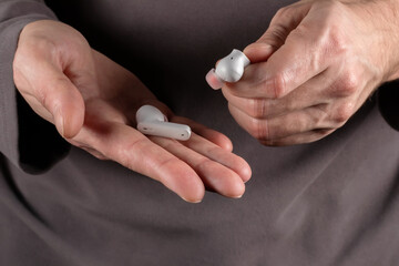 Wireless in-ear white headphones in hand