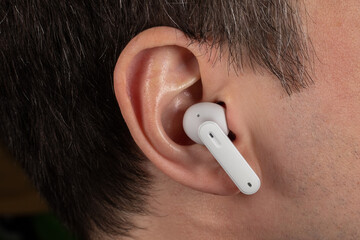 White wireless headphones in ear. Close up