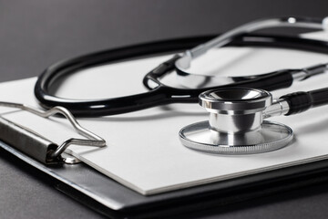 A stethoscope with white paper on it, set against a dark background