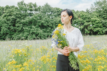 Beautiful girl among the summer field with wildflowers