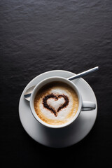 top view cup of coffee with cocoa heart. dark background.latte art coffee