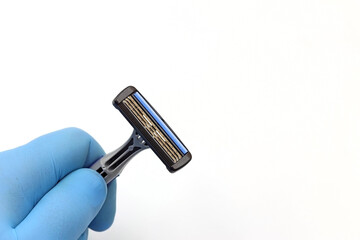 Blue glove holding a three-blade razor. Space for text