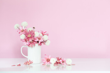 white and pink  chrysanthemums in white cup on pink background