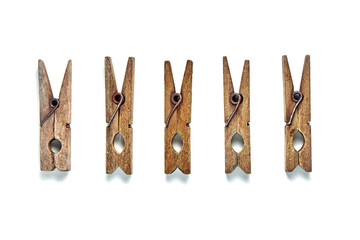 A group of shabby vintage wooden clothespins lie in a row isolated on a white background