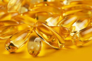 Three capsules Omega 3 on yellow background and many other of capsules on blurred background. Health care concept