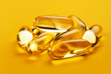 Fish oil capsules with omega 3 and vitamin D on yellow background