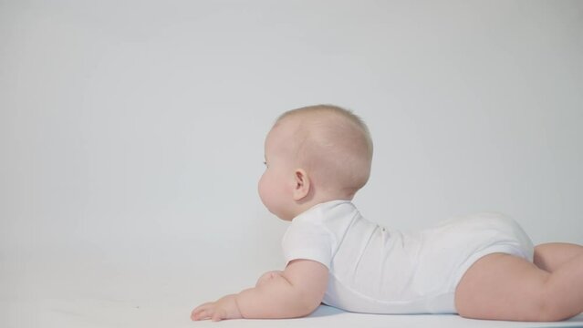 baby on white background learn to roll over, first skills
