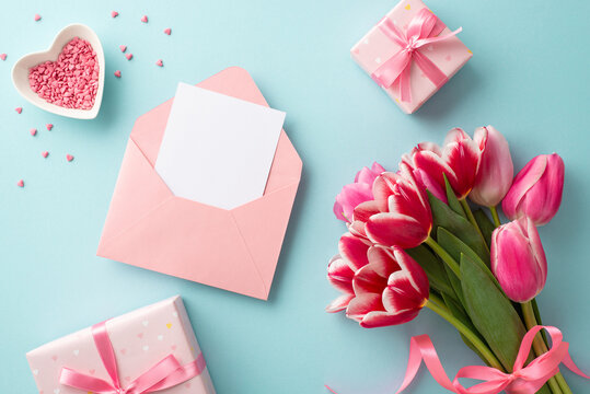Mother's Day concept. Top view photo of bouquet of tulips gift boxes with ribbon bows envelope with paper sheet and heart shaped saucer with sprinkles on isolated pastel blue background with copyspace