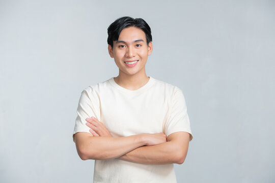 Smiling young Asian man with arms crossed on a white background