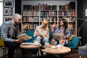 Happy diverse group of college students working together on study project in university library,...