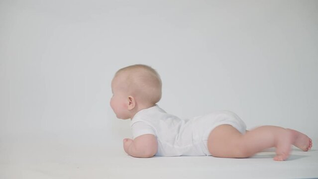 an infant on a white background begins to crawl on its stomach