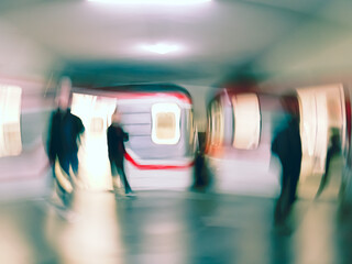 Lens blur image of a subway with moving human silhouettes and a train. Motion blur image of people.