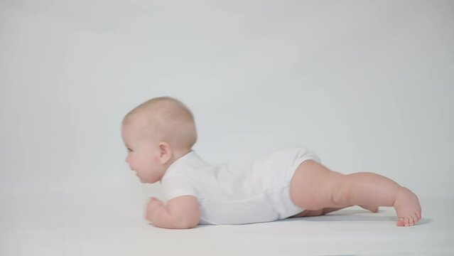an infant on a white background begins to crawl on its stomach. the first acquired skills of human development